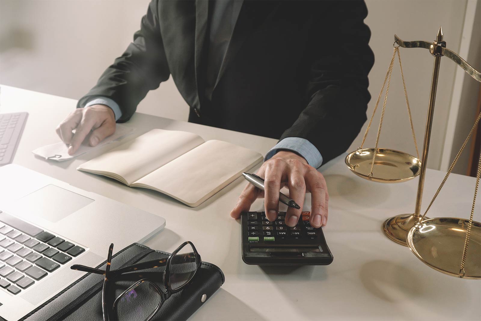 Fotografía de ejecutivo con calculadora, ordenador y balanza de justicia
